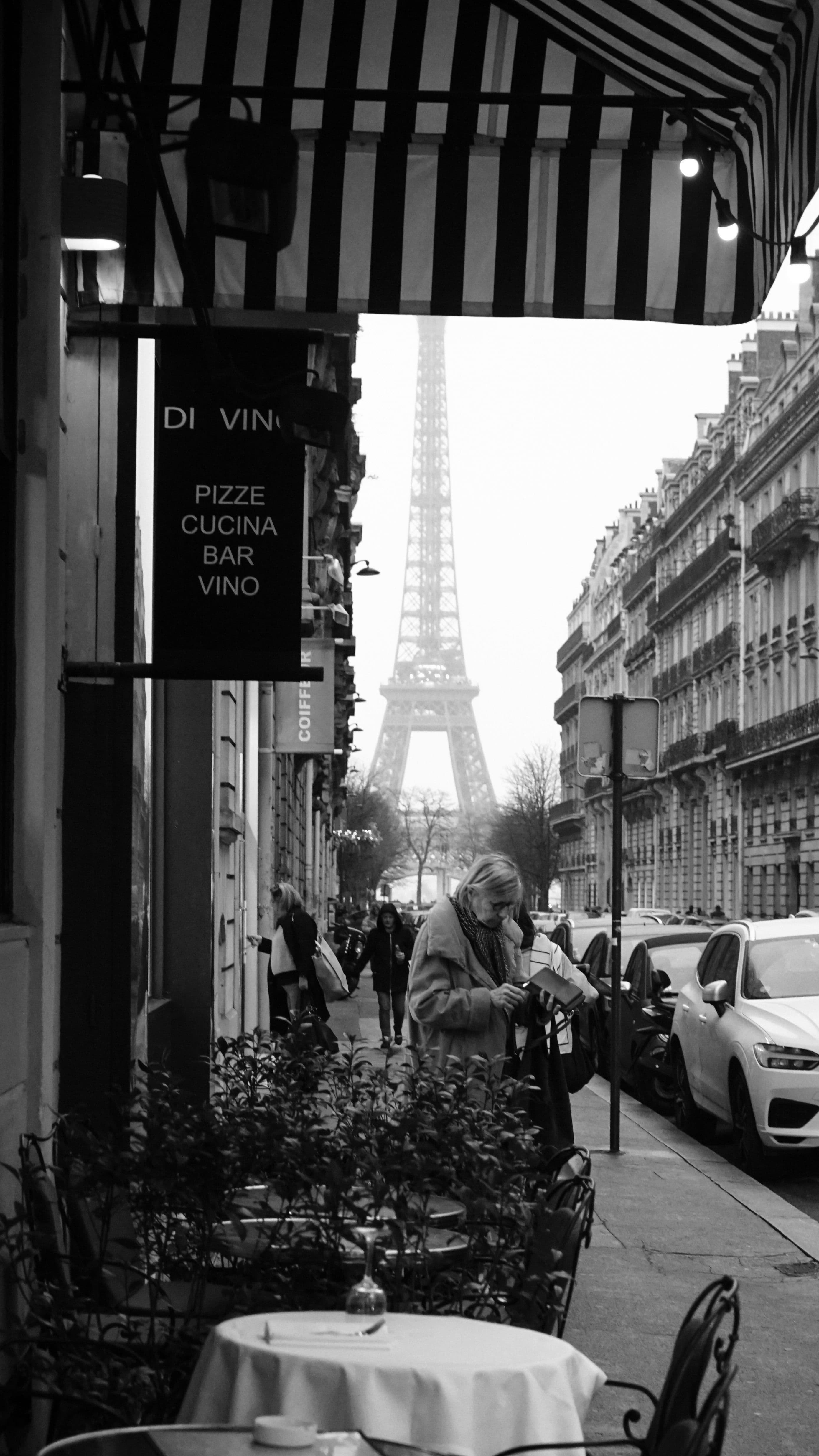 Romantic black and white view of Parisian café with Eiffel Tower in the background.