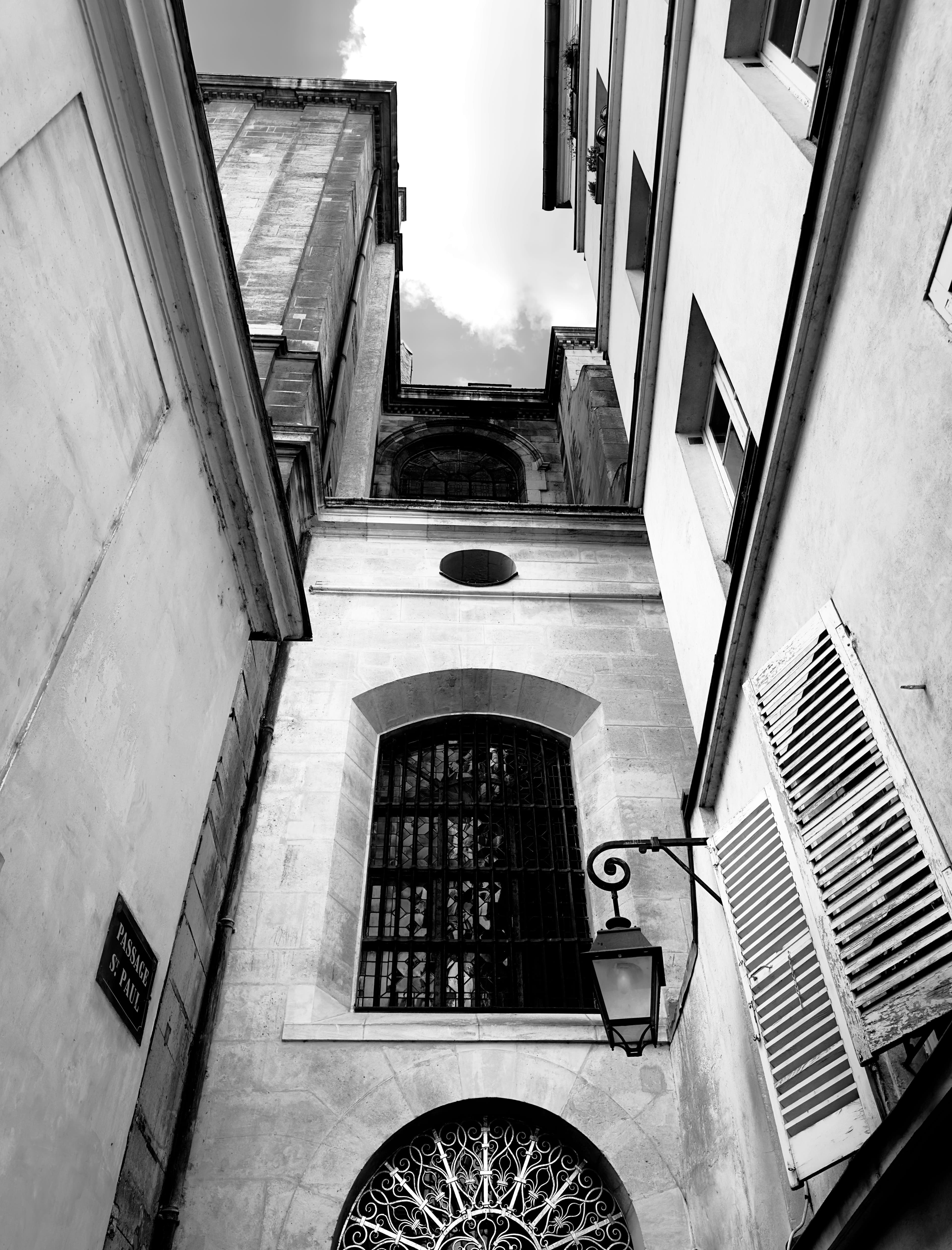 Black and white view of a narrow alleyway with historical architecture and dramatic light.