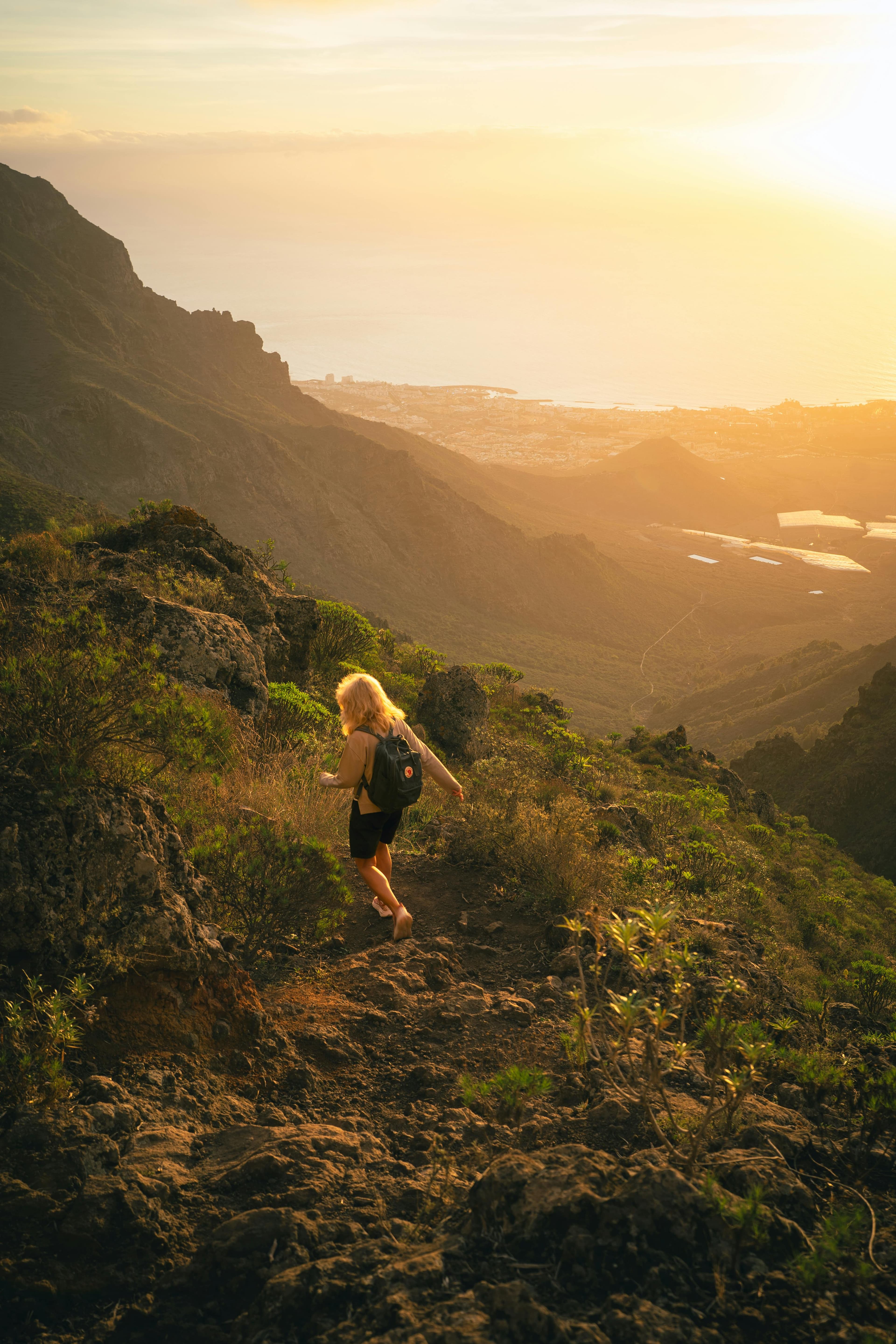 A hiker explores the rugged trails of Ifonche, Spain, during a vibrant sunset.