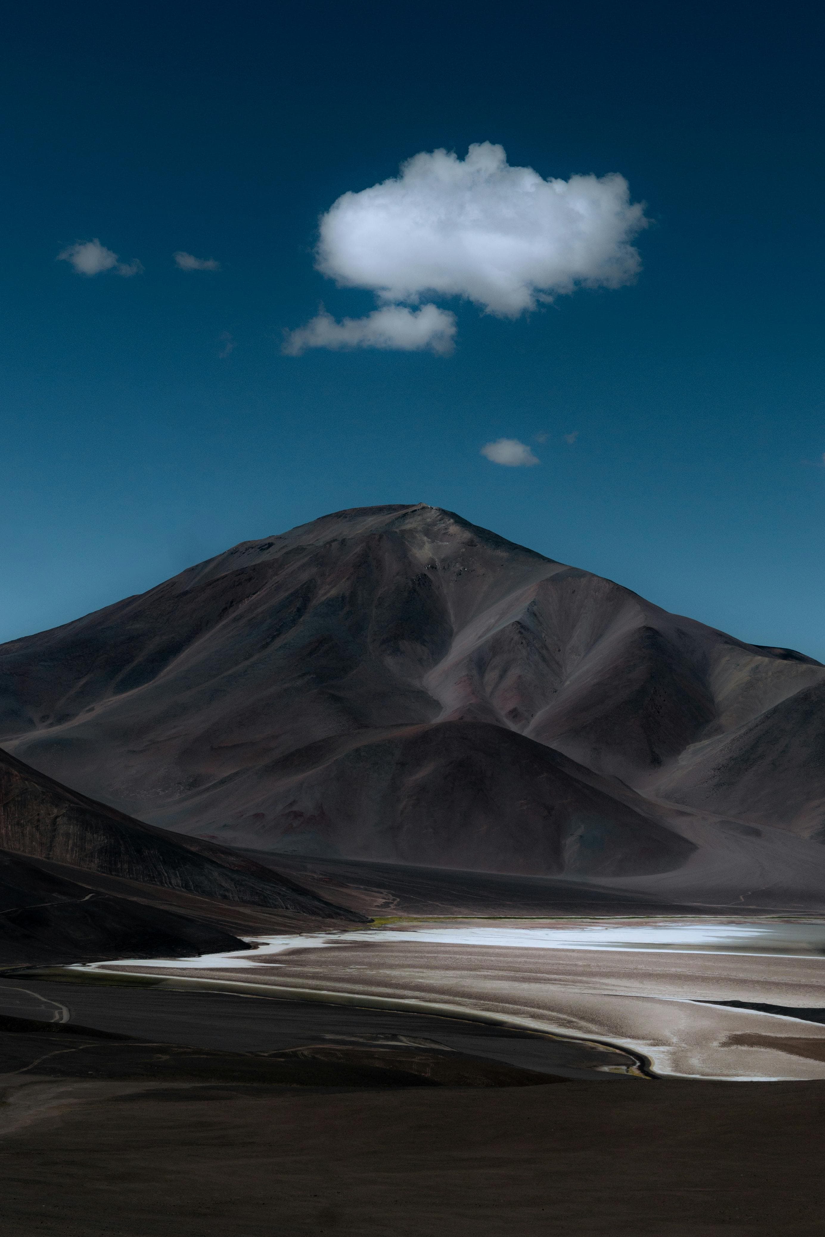 Stunning mountain landscape with a lone cloud and deep blue sky.