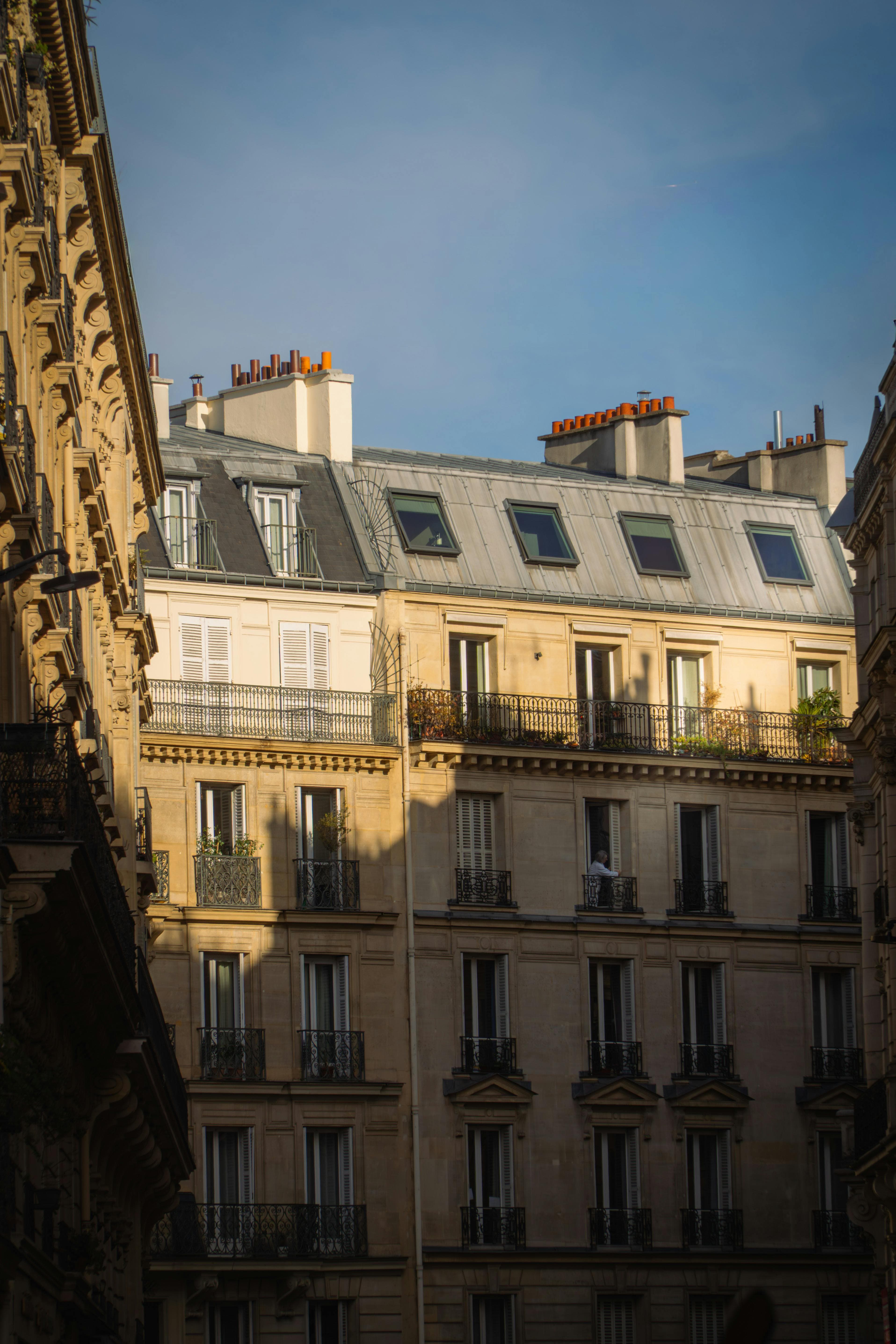 Charming Parisian buildings with sunlight casting shadows in a quiet city street.