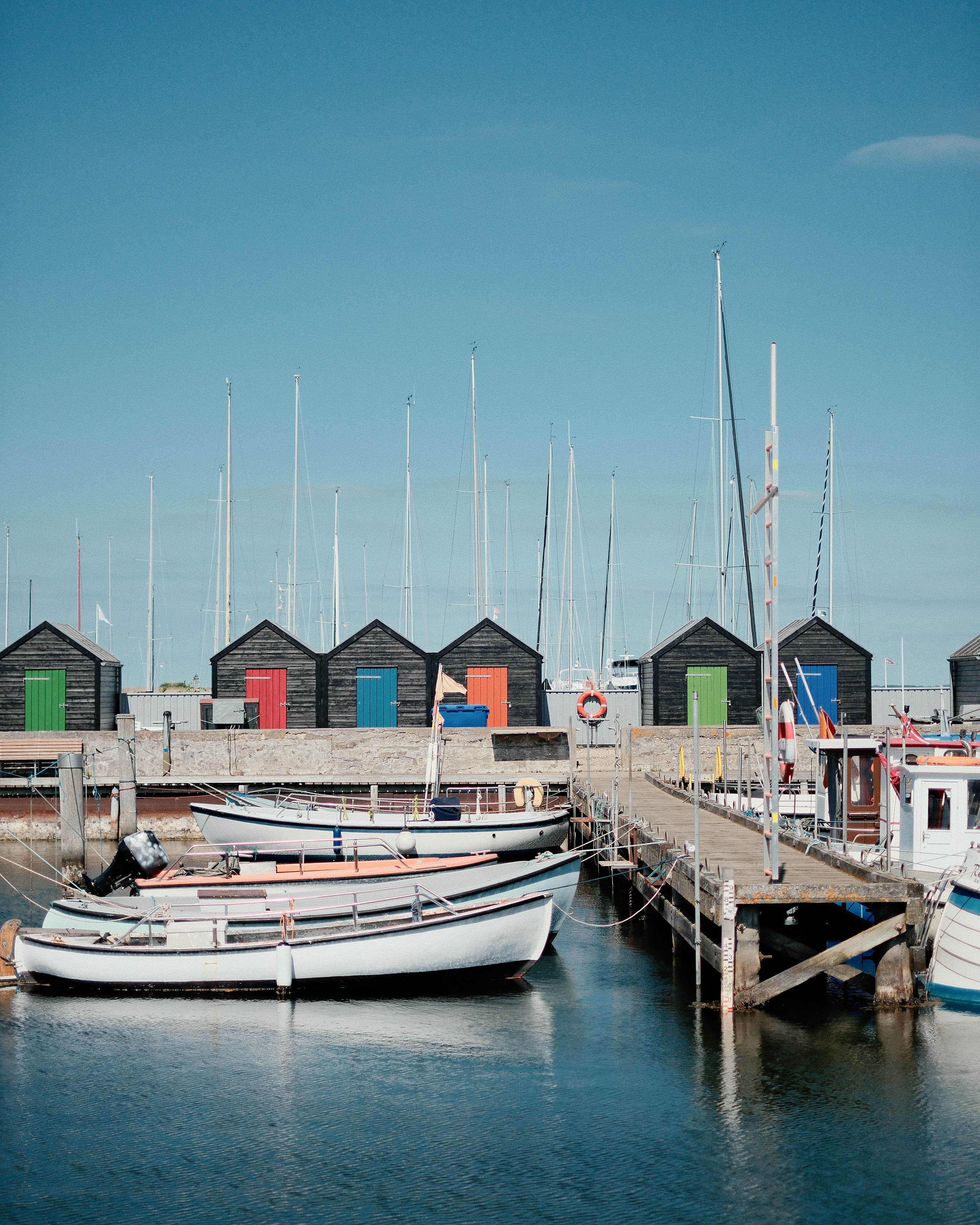 Picturesque harbor in Denmark featuring vibrant boathouses and docked boats under clear skies.