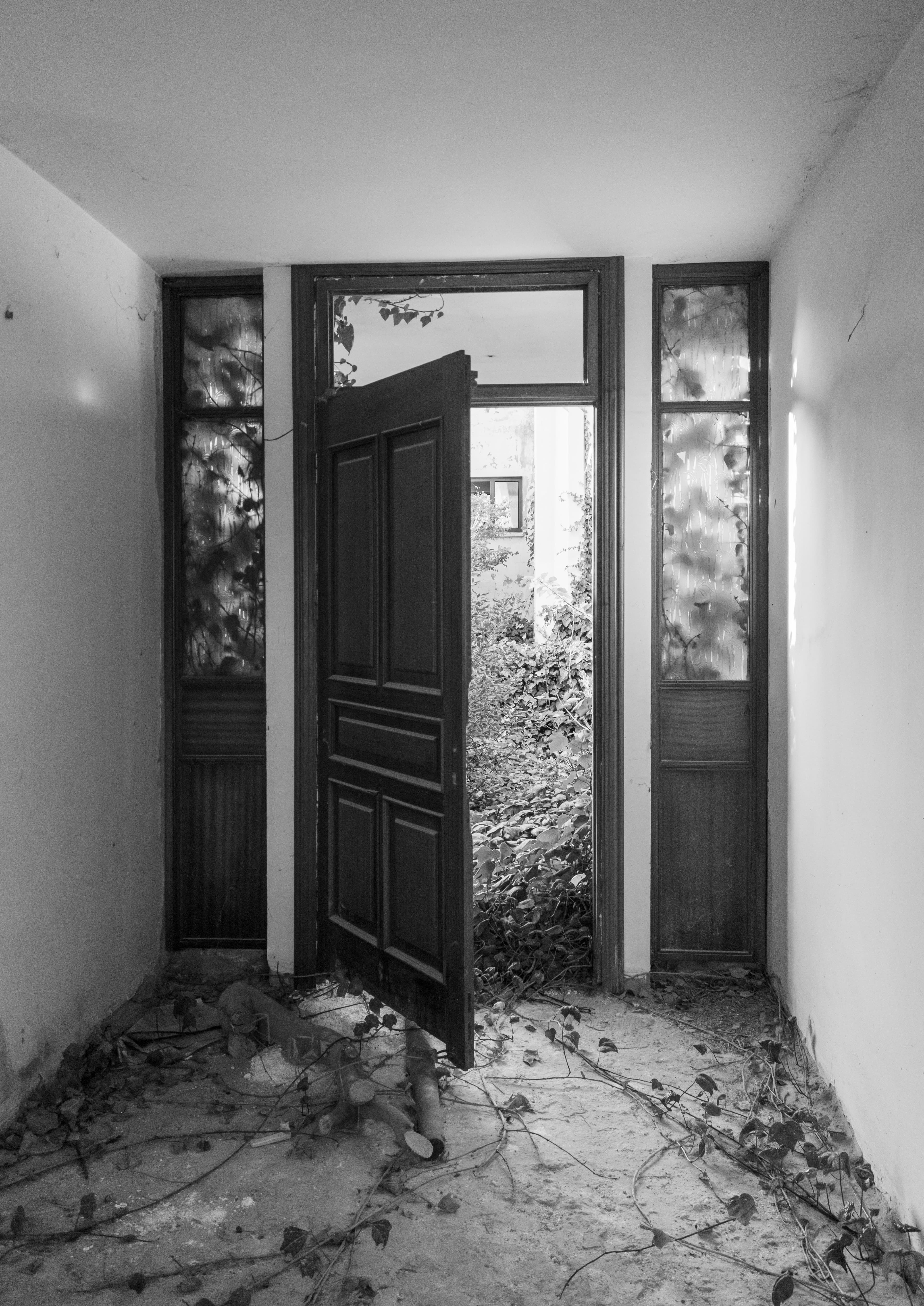 Black and white photo of a decaying hallway and open door