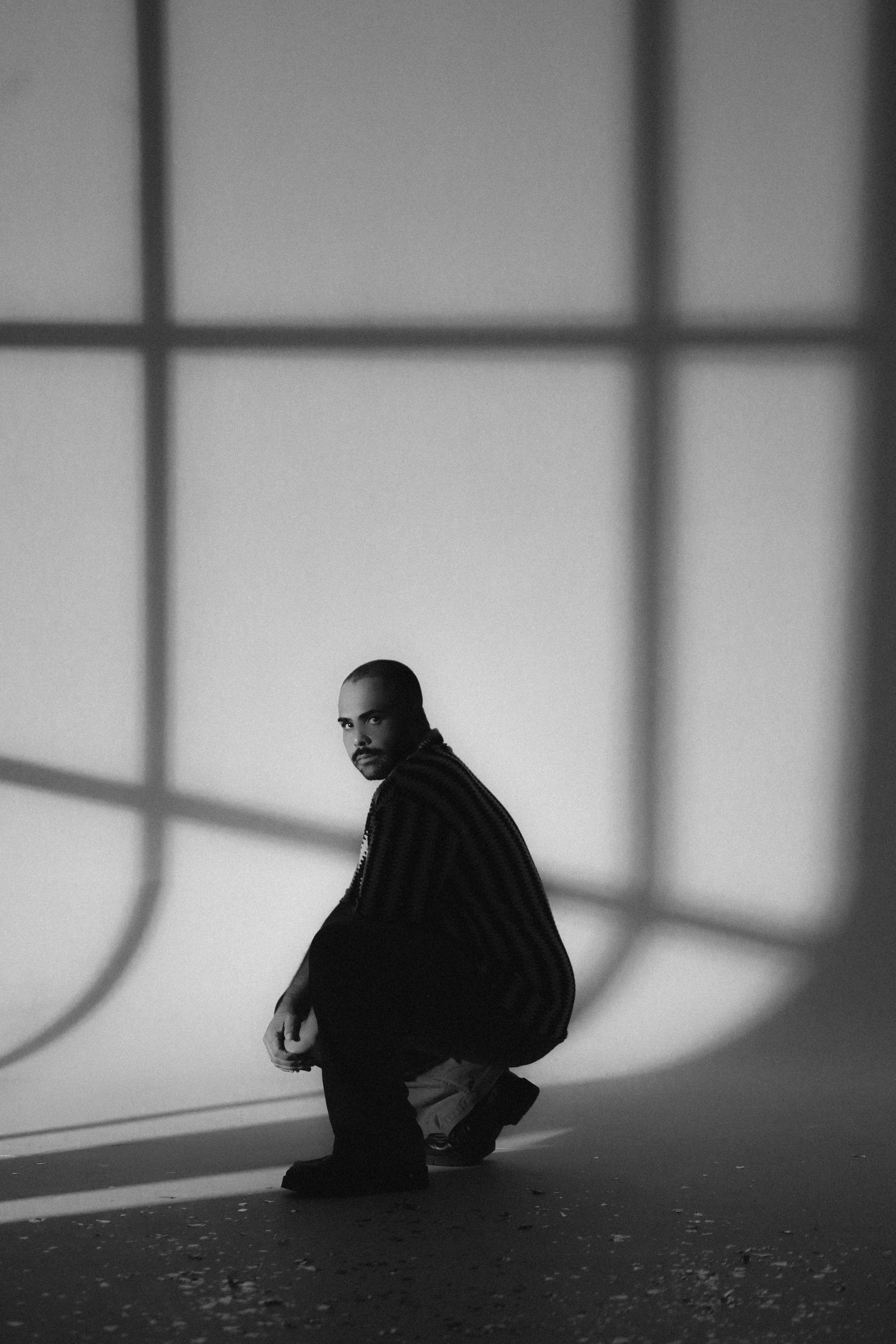 A man crouches in dramatic light and shadows, creating a vintage, moody atmosphere. Perfect for creative projects.