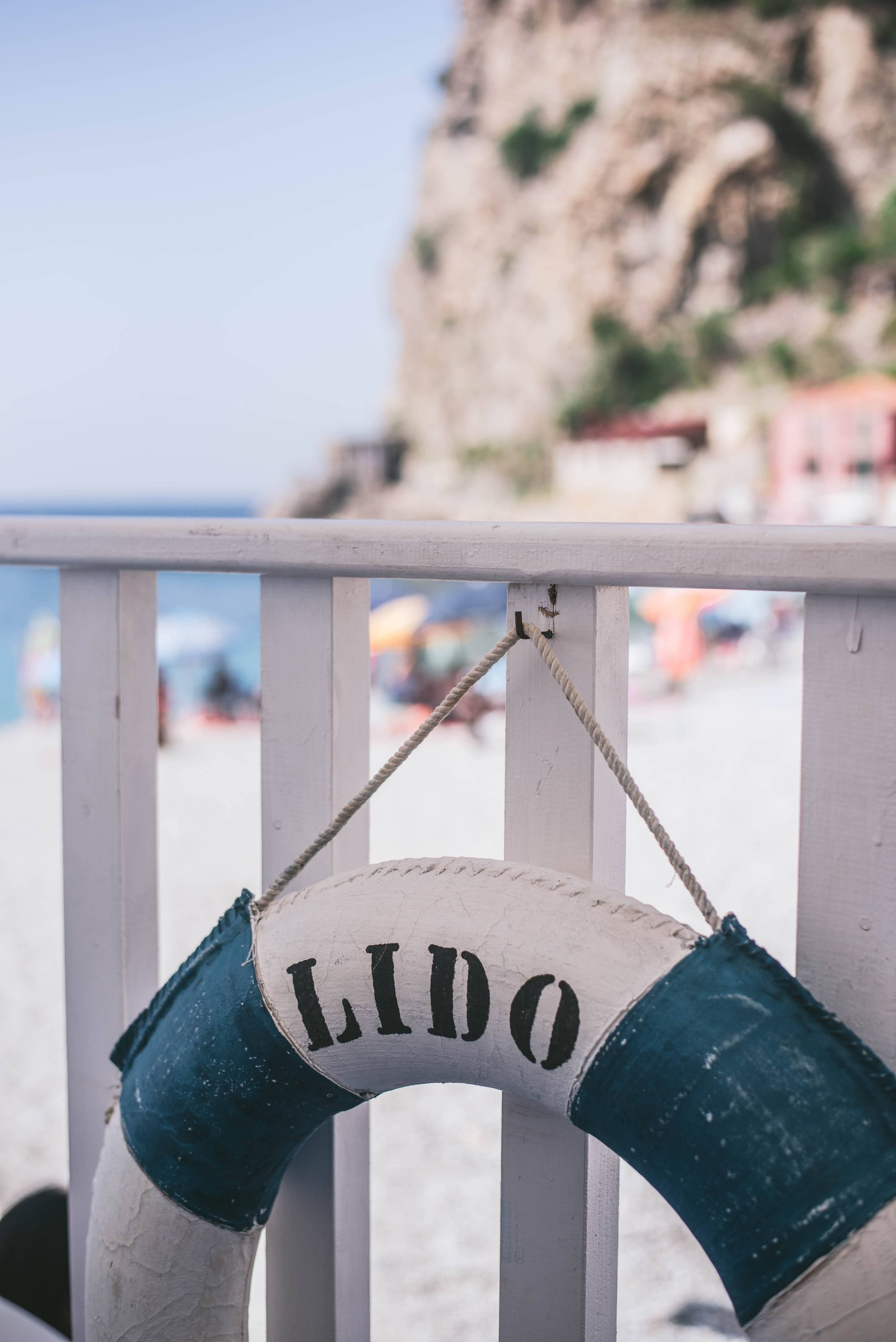 A tranquil beach setting with a life ring labeled 'Lido' against a backdrop of sand and cliffs.